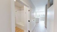 Located at 26 Jerome Ave in Bloomfield, Connecticut, this thoughtfully designed one-bedroom, one-bathroom residence makes efficient use of its compact footprint with a clean, modern aesthetic. Light wood-style flooring flows throughout the space, complementing the crisp white walls and creating a bright, cohesive atmosphere.

The kitchen serves as the centerpiece of the home, showcasing a large white waterfall-edge island with an integrated sink, ideal for both meal preparation and casual dining. Warm-toned wood grain cabinetry lines the walls, providing ample storage, while stainless steel appliances — including a refrigerator, electric range, and over-the-range microwave — deliver a polished, functional cooking environment. A white subway tile backsplash adds a clean, contemporary touch, and pendant lighting overhead enhances the open feel of the space.

The bathroom is finished with the same light wood-style flooring and features a full soaking tub with a curved shower rod and white tiled surround, a wood-accented vanity with a white countertop, and tasteful chrome fixtures. The neutral palette throughout keeps the space feeling open and airy.

Natural light filters in through windows that offer views of the surrounding neighborhood, adding warmth and vitality to this well-appointed Bloomfield residence.