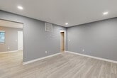 This thoughtfully designed single-floor unit offers a comfortable and functional layout across six distinct spaces, including a living room, kitchen, bedroom, two bathrooms, a closet, and a hallway. The living area is finished with light-toned luxury vinyl plank flooring and cool gray walls, creating a clean, contemporary atmosphere. Recessed lighting and a visible HVAC vent ensure year-round comfort throughout the open space.

The kitchen is well-equipped with a full suite of stainless steel appliances — including a range, microwave, dishwasher, and refrigerator — complemented by white shaker-style cabinetry, granite-look countertops, a subway tile backsplash, and a flush-mount ceiling light.

The generously sized primary bedroom features plush wall-to-wall carpeting, a ceiling fan with integrated lighting, and a window that brings in natural light with views of the surrounding greenery. An adjacent walk-in closet is outfitted with multi-level wire shelving systems and its own window, providing ample storage. One bathroom features wood-look tile flooring and wall surround, a soaking tub, and a white vanity with granite-style countertops. Consistent gray walls and white trim unify the design throughout.