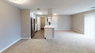 This single-floor residence offers a thoughtfully designed layout that balances comfort and functionality throughout. The open-concept living area features neutral-toned carpet and warm gray walls, creating a bright and versatile space that flows seamlessly into the kitchen. A peninsula counter with a white finish serves as a natural dividing element between the two areas, ideal for casual dining or additional prep space.

The kitchen is equipped with stainless steel appliances, including a refrigerator, electric range, and over-the-range microwave. White shaker-style cabinetry lines the walls, paired with light countertops and durable wood-look flooring that adds warmth and easy maintenance to the space.

The bedrooms are generously sized, each finished with soft carpet, gray walls, and white trim. One bedroom features a ceiling fan with a light fixture and a window that brings in natural light with views of greenery outside. An adjoining walk-in closet and direct access to a bathroom enhance the functionality of the primary bedroom.

The bathroom is clean and bright, offering a full tub and shower combination with subway tile surround, a single vanity with white cabinetry, built-in overhead storage, and chrome fixtures. The consistent use of neutral tones and white finishes throughout the space creates a cohesive, move-in ready aesthetic.