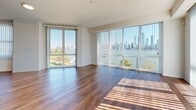 Located at 1600 Harbor Blvd in Weehawken, NJ, this well-appointed 3-bedroom, 2-bathroom residence offers a thoughtfully designed single-floor layout with generous living space. Warm hardwood flooring flows throughout the main living areas and bedrooms, creating a cohesive and inviting ambiance. The open-concept kitchen and living room serve as the heart of the home, anchored by a sleek center island with a light stone countertop, dark cabinetry, and a full suite of stainless steel appliances including a refrigerator, microwave, and range. Pendant lighting and large windows with vertical blinds fill the space with natural light and frame outdoor views of the surrounding area. The spacious primary bedroom enjoys an abundance of natural light through large windows, while the additional bedrooms offer comfortable proportions and hardwood flooring. Both bathrooms are finished with large-format tile floors, dark wood vanities with light countertops, and frameless mirrors. One bathroom features a walk-in shower, while the other offers a full soaking tub. The unit also includes a dedicated laundry area, two hallways, and an impressive eight closets providing exceptional storage throughout. Clean white walls and modern panel doors complete the refined, contemporary aesthetic.