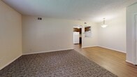 Located at 1521 S Third St in Louisville, KY, this single-floor, one-bedroom, one-bathroom unit offers a straightforward and functional layout. The living area is spacious and open, featuring a combination of patterned carpet and hardwood-style flooring, neutral cream-toned walls, and a textured ceiling. A pendant light fixture adds a subtle decorative touch, and a pass-through view connects the living space to the kitchen, enhancing the sense of openness. The kitchen is equipped with dark wood cabinetry, a white refrigerator, and a range, providing practical functionality in a compact footprint. The bedroom is a comfortable, well-proportioned room carpeted throughout, featuring a large double-door louvered closet for ample storage and a window that allows natural light to fill the space. The bathroom includes a full tub and shower combination with chrome fixtures and a curtain enclosure, accompanied by a toilet and tiled flooring. Throughout the unit, the consistent use of neutral tones and clean white trim creates a cohesive, understated aesthetic. Windows in both the living area and bedroom bring in natural light, contributing to a bright and livable atmosphere well-suited for everyday comfort.