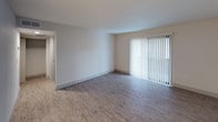 This single-floor unit offers a clean, modern layout designed for comfortable everyday living. The galley-style kitchen is a standout feature, equipped with white shaker cabinetry, granite countertops, a stainless steel sink, and a full suite of stainless steel appliances including a refrigerator, electric range, microwave, and dishwasher. Light wood-look flooring and subway tile backsplash complete the kitchen's contemporary aesthetic.

The living area is open and airy, benefiting from a large sliding glass door fitted with vertical blinds that allows abundant natural light to fill the space. Wood-look flooring continues throughout this area, contributing to a cohesive and modern feel. An adjacent open area with light wood flooring provides flexible use as a dining or additional living space, with a view into the kitchen.

The bedroom features plush wall-to-wall carpeting and a ceiling fan with an integrated light fixture, along with a window with vertical blinds that offers views of the outdoors. The full bathroom is thoughtfully finished with a granite-topped vanity, white cabinetry, wood-look flooring, and a tub/shower combination surrounded by clean gray subway tile. Throughout the unit, neutral wall tones and consistent finishes create a bright, move-in-ready environment.