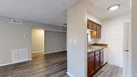 This efficiently designed 1-bedroom, 1-bathroom single-floor unit offers a functional and comfortable layout across a compact yet well-utilized footprint. The combined kitchen and living area serves as the heart of the space, featuring durable hardwood-style flooring in a rich gray-toned finish that extends throughout the unit. The kitchen is equipped with rich wood cabinetry, granite-style countertops, a double basin sink, and a dishwasher, and is separated from the living area by a half-wall partition that maintains an open, connected feel. The living room is bright and neutral, with soft gray walls, a textured ceiling, and a sliding door that allows in natural light. The bedroom is a generously sized retreat complete with a ceiling fan light fixture, a dedicated closet, and direct access to the full bathroom. The bathroom features a tub-shower combination, a toilet, and a vanity with granite-style countertops and a mirror. A hallway connects the main living areas to the private spaces, contributing to the unit's logical and practical flow. Neutral tones, consistent flooring, and clean finishes throughout create a cohesive and move-in-ready environment.