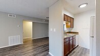 This efficiently designed 1-bedroom, 1-bathroom single-floor unit offers a functional and comfortable layout across a compact yet well-utilized footprint. The combined kitchen and living area serves as the heart of the space, featuring durable hardwood-style flooring in a rich gray-toned finish that extends throughout the unit. The kitchen is equipped with rich wood cabinetry, granite-style countertops, a double basin sink, and a dishwasher, and is separated from the living area by a half-wall partition that maintains an open, connected feel. The living room is bright and neutral, with soft gray walls, a textured ceiling, and a sliding door that allows in natural light. The bedroom is a generously sized retreat complete with a ceiling fan light fixture, a dedicated closet, and direct access to the full bathroom. The bathroom features a tub-shower combination, a toilet, and a vanity with granite-style countertops and a mirror. A hallway connects the main living areas to the private spaces, contributing to the unit's logical and practical flow. Neutral tones, consistent flooring, and clean finishes throughout create a cohesive and move-in-ready environment.