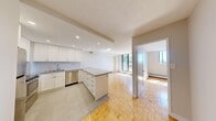 This efficiently designed one-bedroom, one-bathroom unit makes excellent use of its compact footprint across a single floor. Warm parquet flooring runs throughout the main living areas and bedroom, lending a classic character to the space. The open-concept kitchen flows directly into the living room, creating a cohesive and functional layout. The kitchen is well-appointed with white shaker-style cabinetry, stainless steel appliances including a refrigerator, stove, microwave, and dishwasher, recessed lighting, and a peninsula that provides additional counter space and separates the kitchen from the living area. Tile flooring grounds the kitchen zone distinctly within the open plan. The living room benefits from generous natural light through a sliding glass door that opens onto a balcony, offering views of surrounding greenery and the outdoors. Baseboard heating units are present throughout the unit. The bedroom is a comfortable, well-proportioned room featuring parquet flooring, a window that invites natural light, and a built-in sliding door closet. The bathroom is finished with clean white subway tile surrounding a bathtub and shower combination, complemented by chrome fixtures for a crisp, modern feel.