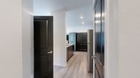 Located at 5130 W Expo Pkwy in Post Falls, Idaho, this 2-bedroom, 1-bathroom unit offers a clean, modern aesthetic throughout its single-level floor plan. The interior design is defined by a consistent palette of crisp white walls, light wood-style luxury vinyl plank flooring in the main living areas, and bold dark-paneled doors that provide striking contrast throughout the space.

The kitchen serves as a functional centerpiece, featuring dark cabinetry with a warm wood tone, light stone-look countertops, stainless steel appliances including a refrigerator and microwave, and a peninsula that opens toward the living area. A large pantry with dark double doors adds practical storage. Recessed lighting illuminates the kitchen efficiently.

The living room is bright and open, with large windows and a sliding glass door that invite natural light and provide views of the surrounding neighborhood. Light flooring and white walls keep the space feeling airy and versatile.

Both bedrooms are carpeted for comfort and include dark double-door closets. The secondary bedroom features a window with an outdoor view. The shared bathroom is well-appointed with a dual-sink vanity, light stone countertops, dark cabinetry, a large mirror, and wood-style flooring, offering both style and functionality.