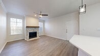 This single-story, 3-bedroom, 1-bathroom home offers a thoughtfully designed layout that maximizes functionality and comfort. The open-concept kitchen and living area serves as the heart of the home, featuring a central island with a white quartz countertop, stainless steel appliances, white shaker cabinetry, a subway tile backsplash, and a skylight that fills the space with natural light. Industrial-style pendant lights hang above the island, adding a modern touch. The adjoining living room is highlighted by a striking chevron-tiled fireplace with a rustic wood mantel, crown molding, a ceiling fan, and windows that invite natural light from multiple angles. Durable wood-look flooring runs throughout the main living areas, while plush carpet adds warmth to the bedrooms. The primary bedroom is generously sized and features a sliding glass door that opens to an outdoor area with serene wooded views. The full bathroom is clean and functional, equipped with a tub-shower combination and overhead cabinetry for storage. A dedicated in-unit laundry room houses a full-size washer and dryer. The home also includes a hallway closet and a connected hallway that ties all rooms together in an efficient, easy-to-navigate floor plan.