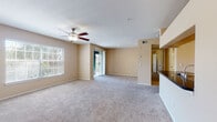 This single-floor residence offers a functional and comfortable layout designed for everyday living. The spacious open-concept living area is finished with plush carpeting and features a ceiling fan with light fixture, a large window with blinds for natural light, and a sliding glass door providing access to an outdoor space. Warm beige walls throughout create a cohesive, neutral palette across all rooms.

The kitchen is equipped with stainless steel appliances, including a full-size refrigerator and a gas range with oven, complemented by light wood cabinetry and dark granite-style countertops. Wood-look flooring runs through the kitchen and connects seamlessly to an adjacent in-unit laundry room, which houses a full-size washer and dryer.

The bathroom features a tiled tub-shower combination, wood-look flooring, and dark countertop finishes consistent with the kitchen. Bedrooms are carpeted and generously sized, each fitted with a ceiling fan. One bedroom includes a sliding door to the outdoor area, while another features a walk-in closet with built-in shelving and hanging rods, offering excellent storage capacity. The overall layout is practical, well-lit, and move-in ready.