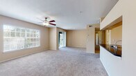 This single-floor residence offers a functional and comfortable layout designed for everyday living. The spacious open-concept living area is finished with plush carpeting and features a ceiling fan with light fixture, a large window with blinds for natural light, and a sliding glass door providing access to an outdoor space. Warm beige walls throughout create a cohesive, neutral palette across all rooms.

The kitchen is equipped with stainless steel appliances, including a full-size refrigerator and a gas range with oven, complemented by light wood cabinetry and dark granite-style countertops. Wood-look flooring runs through the kitchen and connects seamlessly to an adjacent in-unit laundry room, which houses a full-size washer and dryer.

The bathroom features a tiled tub-shower combination, wood-look flooring, and dark countertop finishes consistent with the kitchen. Bedrooms are carpeted and generously sized, each fitted with a ceiling fan. One bedroom includes a sliding door to the outdoor area, while another features a walk-in closet with built-in shelving and hanging rods, offering excellent storage capacity. The overall layout is practical, well-lit, and move-in ready.