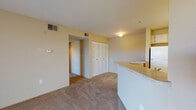 This single-floor residence is designed with a functional, open layout that connects the kitchen and living areas seamlessly. The kitchen is equipped with light wood cabinetry offering ample upper and lower storage, a white electric range, a full-size refrigerator, and a double-basin stainless steel sink. Granite-style countertops extend along the workspace and wrap around a peninsula that separates the kitchen from the carpeted living area, creating a natural boundary while maintaining an open feel.

The living space is finished with neutral-toned carpet and warm yellow walls, lending a cohesive and comfortable atmosphere throughout. Bedrooms continue the same carpeted flooring and feature ceiling fans with light fixtures, windows with vertical blinds that bring in natural light, and generous closet space. One bedroom includes a spacious walk-in closet with wire shelving, while additional louvered-door closets provide further built-in storage.

The bathroom features a light wood vanity with a granite-style countertop, a large mirror illuminated by a strip of vanity lights, tile flooring, and a shower-tub combination. The unit also benefits from overhead ventilation throughout and a private entry door, contributing to an overall practical and comfortable living environment.