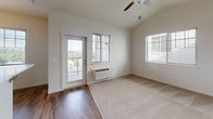 This single-floor unit presents a well-organized layout with a clean, contemporary aesthetic defined by neutral tones, warm wood-look flooring, and abundant natural light. The open-concept living and dining area serves as the heart of the space, featuring vaulted ceilings, wood-look hard flooring, a ceiling fan, and multiple windows that invite natural light. A glass door provides direct access to a private balcony with outdoor views. The living area transitions seamlessly into the kitchen via a breakfast bar with barstool seating, ideal for casual dining. The kitchen is well-appointed with flat-front light wood cabinetry, white countertops, a double sink, and black appliances including a range, microwave, and dishwasher. A pendant chandelier and recessed lighting complete the space. Two bedrooms feature plush carpeting and windows overlooking the surrounding neighborhood. Both bathrooms are finished in bright, neutral tones with light wood vanities, white countertops, and tile flooring. One bathroom includes a walk-in shower, while the other offers a combined tub-shower setup. Overall, the unit delivers a fresh, move-in-ready atmosphere with a cohesive and modern design sensibility.