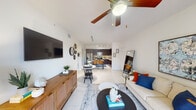 This single-floor residence is designed with an open, flowing layout that seamlessly connects the main living spaces. The living room is bright and welcoming, featuring light tile flooring, a ceiling fan, and a sliding glass door that fills the space with natural light and provides direct access to an outdoor area. A comfortable seating arrangement anchors the room alongside a dining area, creating a versatile and functional space.

The kitchen is outfitted with rich dark wood cabinetry extending to the ceiling, white countertops, stainless steel appliances including a range, microwave, and dishwasher, and track lighting overhead. A kitchen island with bar seating adds additional prep and dining space.

The bedroom is serene and well-proportioned, featuring wood-style flooring, a ceiling fan, and a window with views to the outdoors. The bathroom includes a full soaking tub with a shower curtain setup and tile surround, finished in neutral tones.

A dedicated in-unit laundry room with a full-size washer and dryer adds significant convenience. Throughout the unit, white walls and consistent tile flooring create a cohesive, clean aesthetic.