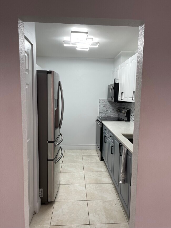 La casa es completamente blanca, pero la iluminación hace que la pared parezca ligeramente rosada. - 13909 SW 57th Ln