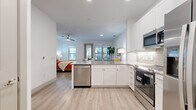 This one-bedroom, one-bathroom unit offers an efficiently designed single-level layout that maximizes its compact footprint. The open-concept floor plan connects the kitchen directly to the main living and sleeping area, creating a cohesive and functional living space throughout.

The kitchen is outfitted with white shaker cabinetry, granite countertops, a subway tile backsplash, and a full suite of stainless steel appliances, including a dishwasher, range, over-the-range microwave, and a side-by-side refrigerator with an ice and water dispenser. A peninsula counter provides additional workspace and separation between the kitchen and the living area.

The generously sized primary bedroom accommodates both sleeping and living functions, featuring a ceiling fan, recessed lighting, and large windows that bring in natural light. A sliding door provides direct access to a private balcony with outdoor views. Light wood-tone luxury vinyl plank flooring runs consistently throughout the unit.

The bathroom includes a tub-shower combination with marble-style tile surround, a granite-topped vanity with white cabinetry, and wood-tone flooring. A dedicated entryway houses a stacked in-unit washer and dryer, adding notable convenience. A closet completes the layout.