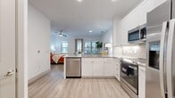 This one-bedroom, one-bathroom unit offers an efficiently designed single-level layout that maximizes its compact footprint. The open-concept floor plan connects the kitchen directly to the main living and sleeping area, creating a cohesive and functional living space throughout.

The kitchen is outfitted with white shaker cabinetry, granite countertops, a subway tile backsplash, and a full suite of stainless steel appliances, including a dishwasher, range, over-the-range microwave, and a side-by-side refrigerator with an ice and water dispenser. A peninsula counter provides additional workspace and separation between the kitchen and the living area.

The generously sized primary bedroom accommodates both sleeping and living functions, featuring a ceiling fan, recessed lighting, and large windows that bring in natural light. A sliding door provides direct access to a private balcony with outdoor views. Light wood-tone luxury vinyl plank flooring runs consistently throughout the unit.

The bathroom includes a tub-shower combination with marble-style tile surround, a granite-topped vanity with white cabinetry, and wood-tone flooring. A dedicated entryway houses a stacked in-unit washer and dryer, adding notable convenience. A closet completes the layout.