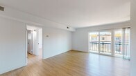 Located at 520 Kelton Ave in the highly sought-after Westwood neighborhood of Los Angeles, this single-floor unit showcases a clean, modern aesthetic throughout. Light wood laminate flooring runs continuously across the living areas, bedrooms, and entry, lending a warm and cohesive feel to the space.

The open living area is bright and airy, with large sliding glass doors that lead to a private balcony offering views of the surrounding neighborhood and mature trees. A ceiling fan adds both comfort and character to the space.

The kitchen is thoughtfully appointed with white shaker-style cabinetry featuring matte black hardware, dark quartz countertops, a stainless steel sink with a gooseneck faucet, and stainless steel appliances including a refrigerator, range, and dishwasher — all set against the same warm wood flooring.

The bedroom is generously sized and features floor-to-ceiling mirrored sliding closet doors, maximizing both storage and the sense of space. A second bedroom or flex room includes a window with blinds, allowing for natural light. The bathrooms are finished in a crisp, contemporary style, with tile flooring, white vanities with dark countertops, matte black fixtures, and a glass-enclosed shower. The overall palette of white walls and natural tones creates a fresh, move-in-ready environment.