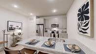 Located at 380 Crown Dr in Emerson, GA, this well-appointed one-bedroom, one-bathroom unit offers a thoughtfully designed single-floor layout with efficient use of space throughout. The open-concept kitchen and living area serves as the heart of the home, where light gray shaker cabinetry, a white subway tile backsplash, and gleaming granite countertops create a clean, modern aesthetic. A peninsula island with an undermount sink provides additional prep space and casual seating, while a full suite of stainless steel appliances—including a French door refrigerator, electric range, and built-in microwave—completes the kitchen. Light hardwood-style flooring flows through the main living areas, enhancing the bright, airy feel. The living room benefits from natural light streaming through floor-to-ceiling curtained windows and is finished with recessed lighting overhead. The bedroom is a calm retreat, featuring plush carpeting, a large window with decorative draping, and an accent wall with a muted green tone. The bathroom offers a double-sink granite vanity with gray shaker cabinetry and stylish matte black fixtures. A dedicated laundry room with full-size washer and dryer adds everyday convenience, along with built-in shelving for additional storage.
