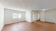Located at 1200 Southwood Pkwy in Richmond, Virginia, this two-bedroom, one-bathroom single-floor home offers a practical and well-organized layout. Warm hardwood-style flooring flows throughout the main living areas and bedrooms, complemented by crisp white walls and textured ceilings that lend a clean, consistent aesthetic throughout.

The open combined living and dining area serves as the heart of the home, featuring a double-panel front entry door that brings in natural light and creates an inviting entryway. The space transitions seamlessly toward the kitchen, which is equipped with oak cabinetry, dark stone-toned countertops, a double sink, and white appliances including a range and refrigerator. A window above the sink adds natural light, while tile-style flooring grounds the functional workspace.

Both bedrooms are comfortably proportioned, with the primary bedroom offering generous square footage, hardwood-style floors, and a window with outdoor views. The home includes four closets in total, providing ample storage throughout. The full bathroom features a single-sink oak vanity, a tub-shower combination, built-in shelving, and tile flooring, maintaining the home's clean and functional character.