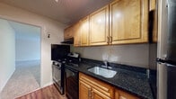 This single-floor residence offers a practical and comfortable layout designed for everyday living. The kitchen is a standout feature, outfitted with warm honey-toned wood cabinetry offering generous upper and lower storage, dark granite countertops, a stainless steel sink, and a gas range — all complemented by durable hardwood-style flooring that adds a polished finish to the space.

The living area is generously proportioned, wrapped in neutral-toned walls and covered with plush carpeting that extends throughout. Large windows fitted with vertical blinds allow natural light to flow in, creating a bright and welcoming atmosphere. A ceiling-mounted light fixture provides additional illumination.

The bedroom is well-sized, featuring soft carpeting, neutral walls, and an abundance of storage with two sets of double bi-fold closet doors, offering ample space for organization.

The bathroom is cleanly finished with large-format marble-patterned floor and wall tiles, a full soaking tub with an overhead shower, and a classic white toilet — lending the room a crisp, tidy appearance.

Overall, this residence presents a cohesive, functional design with consistent neutral finishes throughout, making it a comfortable and move-in ready space.