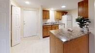 Located at 10 Center in Merrimack, New Hampshire, this single-floor unit offers a thoughtfully laid-out living space with a cohesive design throughout. The kitchen serves as a practical hub, featuring warm wood cabinetry, granite-style countertops, a center island for additional prep and dining space, and white appliances including a refrigerator and dishwasher. Recessed lighting and light tile flooring give the kitchen a clean, bright feel.

The living areas are finished with gleaming hardwood floors and neutral cream-toned walls that create a warm, inviting atmosphere. Sliding glass doors open to an outdoor balcony, allowing natural light to flow in and providing views of the surrounding wooded landscape. Baseboard heating and wall-mounted air conditioning units ensure year-round comfort.

The bedrooms are generously sized, each with hardwood flooring and ample natural light. One bedroom includes direct balcony access, while another features a bifold-door closet. A spacious walk-in closet with wire shelving on both sides offers excellent storage capacity.

The bathroom is well-equipped with a wide vanity featuring warm wood cabinetry, a white countertop, a mirrored medicine cabinet, and tile flooring. Clean white trim and six-panel doors are consistent throughout, contributing to the unit's cohesive, move-in-ready presentation.
