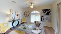 This single-floor residence offers a thoughtfully designed layout with a cohesive, contemporary aesthetic. The living room serves as the heart of the home, highlighted by an elegant arched window that fills the space with natural light, warm hardwood-style flooring, and a ceiling fan overhead. Contemporary artwork and stylish furnishings contribute to an inviting atmosphere.

The kitchen is a standout feature, showcasing crisp white cabinetry, granite countertops, and a full suite of stainless steel appliances including a refrigerator, range, microwave, and dishwasher. A peninsula with bar seating and pendant lighting above creates a functional and social cooking space, while the adjacent dining area provides additional flexibility.

The bedrooms are carpeted and comfortably scaled, each featuring ceiling fans and generous closet storage. The primary bedroom is distinguished by a signature arched window that mirrors the living area's architectural detail, lending the room a bright, airy quality.

The bathrooms are finished in a clean, neutral palette with light tile flooring and granite-topped vanities. One bathroom features a glass-enclosed walk-in shower, while others offer tub-shower combinations. Throughout the residence, the consistent use of light tones, natural light, and quality finishes creates a cohesive and comfortable living environment.