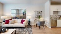 Located at 10191 Main St in Houston, TX, this one-bedroom, one-bathroom residence offers a thoughtfully designed single-floor layout. Light wood-tone flooring flows throughout, complementing the neutral gray-toned walls and recessed lighting that create a bright, cohesive aesthetic.

The open-concept kitchen is a standout feature, showcasing white shaker cabinetry extending to the ceiling, granite countertops, a subway tile backsplash, and a full suite of stainless steel appliances including a range, built-in microwave, and French door refrigerator. A peninsula with seating connects the kitchen seamlessly to the combined dining and living area, which is bathed in natural light from multiple windows and features a ceiling fan overhead.

The living space is generously proportioned, offering room for both a seating arrangement and a functional workspace. The bedroom is a comfortable, well-lit retreat with its own ceiling fan, a large window with outdoor views, and access to a spacious walk-in closet with built-in shelving and hanging rods. A second closet provides additional storage.

The bathroom features white cabinetry, granite countertops, a framed mirror, and stylish vanity lighting. A dedicated laundry area and a welcoming entrance complete this well-appointed residence.
