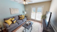 Located at 1408 Teasley Lane in Denton, Texas, this single-floor residence offers a well-organized layout designed for comfortable everyday living. The living room serves as the heart of the unit, featuring warm wood-style flooring, a ceiling fan, a textured ceiling, and a soothing blue-gray accent wall that adds a calming touch to the space. A set of white French doors floods the room with natural light and provides access to the outdoors, creating an open, airy feel. The galley-style kitchen is efficiently laid out with honey-toned wood cabinetry, dark granite-style countertops, a mosaic tile backsplash, and black appliances, including a refrigerator and range. Wood-style flooring continues throughout the kitchen, adding continuity to the design. The bedroom is a restful retreat, highlighted by warm gold-toned accent walls, plush carpeting, a ceiling fan, and a walk-in closet offering generous storage. Natural light filters in through a window with blinds, contributing to the room's welcoming atmosphere. The bathroom is clean and functional, featuring wood-style flooring, a tiled tub-shower combination, and a light wood storage cabinet. Together, the rooms create a cohesive, comfortable living environment suited for a variety of lifestyles.