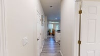 This single-floor residence in Indianapolis, IN offers a thoughtfully designed layout across two bedrooms, three bathrooms, and dedicated living and dining spaces. Light-toned walls and wood-look luxury vinyl flooring run throughout the main living areas, creating a cohesive and clean aesthetic.

The living room provides a comfortable gathering space with neutral walls, and connects naturally to the combined kitchen and dining area. The kitchen is outfitted with white shaker cabinetry, dark stone-look countertops, and black appliances including a range, dishwasher, and refrigerator. The adjacent dining area accommodates a dining set and receives natural light through a window overlooking the exterior.

The primary bedroom features plush carpet flooring, a window for natural light, and direct access to one of the three bathrooms. The second bedroom is similarly finished with carpet and ample space. The bathrooms feature light wood-look flooring, dark countertop vanities, and clean white fixtures. Two closets provide dedicated storage throughout the unit.

A dedicated laundry room houses a full-size washer and dryer, adding convenience. The hallway connecting the rooms is well-lit and spacious, reinforcing the functional flow of the overall floor plan.