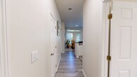 This single-floor residence in Indianapolis, IN offers a thoughtfully designed layout across two bedrooms, three bathrooms, and dedicated living and dining spaces. Light-toned walls and wood-look luxury vinyl flooring run throughout the main living areas, creating a cohesive and clean aesthetic.

The living room provides a comfortable gathering space with neutral walls, and connects naturally to the combined kitchen and dining area. The kitchen is outfitted with white shaker cabinetry, dark stone-look countertops, and black appliances including a range, dishwasher, and refrigerator. The adjacent dining area accommodates a dining set and receives natural light through a window overlooking the exterior.

The primary bedroom features plush carpet flooring, a window for natural light, and direct access to one of the three bathrooms. The second bedroom is similarly finished with carpet and ample space. The bathrooms feature light wood-look flooring, dark countertop vanities, and clean white fixtures. Two closets provide dedicated storage throughout the unit.

A dedicated laundry room houses a full-size washer and dryer, adding convenience. The hallway connecting the rooms is well-lit and spacious, reinforcing the functional flow of the overall floor plan.