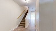 Located at 2 Pierce Dr in Rochester, NH, this two-story home offers four bedrooms and four bathrooms thoughtfully distributed across two floors. The main level provides an open, welcoming layout with light wood-tone flooring throughout the common areas. The kitchen stands out with rich dark wood cabinetry, granite countertops, and stainless steel appliances including a range, microwave, and refrigerator. The main living area features recessed lighting, sliding glass door access to the outdoors, and ample natural light through multiple windows. A carpeted staircase with a warm wood handrail connects the two floors, complemented by clean white walls that create a bright, cohesive aesthetic. The upper level houses the spacious primary bedroom, which includes multiple closets with built-in storage, along with additional well-sized bedrooms, each fitted with carpet flooring and windows that bring in natural light. The bathrooms are finished with wood-tone LVP flooring, granite-topped vanities, and paneled white doors with chrome hardware. Three additional closets throughout the home provide generous storage. The neutral color palette, clean lines, and consistent finishes across both floors give the entire home a polished, move-in-ready feel.