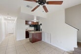 Located in Kissimmee, Florida, this two-story, 3-bedroom, 2-bathroom home offers a practical and comfortable layout spread across two floors. The main level features an open-concept living and kitchen area finished with light ceramic tile flooring. The kitchen is equipped with rich dark wood cabinetry, a granite-topped island, black stainless appliances, and a ceiling fan overhead, creating a functional yet inviting atmosphere. A long, well-lit hallway connects the main living areas and leads toward natural light at the far end.

Upstairs, three carpeted bedrooms each feature ceiling fans and crown molding, providing a warm and comfortable feel. The generously sized primary bedroom includes its own closet access and an adjoining bathroom with dark wood vanity cabinetry, granite countertops, an undermount sink, and a glass-enclosed shower. The second bathroom offers a full tub-shower combo with white tile surround and a matching granite vanity. Each bedroom benefits from ample closet space with wire shelving systems.

A standout feature of this home is the balcony, which overlooks a lush, natural landscape of mature cypress trees draped in Spanish moss, with a pond and wooden deck visible in the background — offering a tranquil, distinctly Floridian outdoor setting.