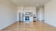 This single-floor residence showcases a clean, contemporary design with a bright, open layout and light wood flooring that runs throughout the entire space. The open-concept kitchen and living area serve as the heart of the unit, where flat-panel white cabinetry extends to the ceiling, providing generous storage. A striking elongated hexagonal tile backsplash frames the cooking area, which is equipped with a full suite of stainless steel Whirlpool appliances, including a range, over-the-range microwave, refrigerator, and dishwasher. Recessed lighting and light-toned countertops complete the polished kitchen aesthetic.

The living area flows seamlessly from the kitchen and opens to a private balcony through floor-to-ceiling sliding glass doors, offering expansive views of the surrounding cityscape and mountains beyond. Natural light pours in generously, enhancing the airy ambiance of the space.

The bedroom features a large picture window framing elevated neighborhood views, while the two bathrooms are finished with modern white vanities, light wood-look flooring, and chrome fixtures. One bathroom includes a soaking tub with a decorative tiled surround, while the second offers a streamlined vanity with a mirrored cabinet. The overall aesthetic is cohesive, minimal, and move-in ready.