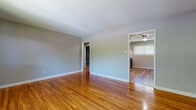 Located at 1291 Burnside Ave in East Hartford, Connecticut, this single-floor unit offers a well-organized layout with a consistent design aesthetic throughout. Polished hardwood flooring in warm honey tones extends across the living areas and bedrooms, contributing to a bright and cohesive interior. Neutral gray walls complement the flooring and provide a clean, versatile backdrop throughout the space.

The living area connects to an adjacent room equipped with a ceiling fan, creating a comfortable flow between spaces. Multiple bedrooms feature hardwood floors, baseboard heating, and windows that bring in natural light with views of surrounding greenery. Several rooms also include wall-mounted air conditioning units for year-round climate control.

The kitchen is well-appointed with white shaker-style cabinetry extending to the ceiling, offering generous storage capacity. Light-toned countertops, a subway tile backsplash, a stainless steel refrigerator, and a stainless range complete the space. Luxury vinyl plank flooring and a ceiling fan add practicality and comfort to the kitchen area.

The bathroom features a full soaking tub with white subway tile surround, accented by a decorative mosaic border, white cabinetry, and a window providing natural ventilation.