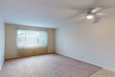 Located at 8842 M St in Omaha, Nebraska, this one-bedroom, one-bathroom unit offers a straightforward and efficient single-floor layout designed for comfortable everyday living. The living room is a welcoming, carpeted space featuring a ceiling fan with integrated lighting and a large sliding glass door dressed with vertical blinds, allowing generous natural light and views of the surrounding neighborhood. The layout transitions smoothly from the carpeted living area into a tiled entryway and kitchen zone, where warm wood-toned cabinetry and a white refrigerator and range provide a functional cooking space. A hallway connects the main living areas to the private quarters of the home. The bedroom is a comfortably sized, carpeted room equipped with its own ceiling fan, a window with vertical blinds for natural light, and a built-in closet offering convenient storage. The bathroom features a full soaking tub and shower combination with textured surround walls and built-in shelving, complemented by tile flooring. Throughout the unit, neutral walls and plush carpet in the main living and sleeping areas create a clean, move-in-ready aesthetic that is easy to personalize.