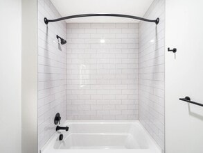 Bathroom with white tile surround, matte black fixtures, and a clean-lined tub and shower design suited to everyday comfort. - Modera Bridle Trails