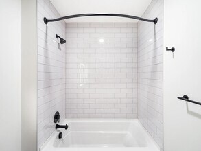 Bathroom with white tile surround, matte black fixtures, and a clean-lined tub and shower design suited to everyday comfort. - Modera Bridle Trails