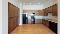 Located at 1335 West Summit Parkway in Spokane, Washington, this single-floor unit offers a clean, modern design with thoughtful finishes throughout. The open-concept living and kitchen area is anchored by warm light hardwood flooring and recessed lighting, creating a bright and welcoming atmosphere. Large windows allow natural light to pour in, offering views of the surrounding community. The kitchen is well-appointed with rich, medium-toned wood cabinetry extending to the upper walls for generous storage, light-colored countertops, and black appliances including a refrigerator, electric range, and built-in microwave. The carpeted bedrooms provide a comfortable retreat, each with sizable windows and ceiling fans to promote airflow. A spacious walk-in closet with wire shelving offers practical storage solutions. The bathrooms feature dark wood vanities with light countertops and a large mirror, with one bath including a full tub-shower combo and hardwood-style flooring. A dedicated laundry area houses a full-size washer and dryer alongside a water heater, adding everyday convenience. The unit's neutral color palette and consistent finishes lend a cohesive, move-in-ready feel throughout the space.