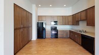 Located at 1335 West Summit Parkway in Spokane, Washington, this single-floor unit offers a clean, modern design with thoughtful finishes throughout. The open-concept living and kitchen area is anchored by warm light hardwood flooring and recessed lighting, creating a bright and welcoming atmosphere. Large windows allow natural light to pour in, offering views of the surrounding community. The kitchen is well-appointed with rich, medium-toned wood cabinetry extending to the upper walls for generous storage, light-colored countertops, and black appliances including a refrigerator, electric range, and built-in microwave. The carpeted bedrooms provide a comfortable retreat, each with sizable windows and ceiling fans to promote airflow. A spacious walk-in closet with wire shelving offers practical storage solutions. The bathrooms feature dark wood vanities with light countertops and a large mirror, with one bath including a full tub-shower combo and hardwood-style flooring. A dedicated laundry area houses a full-size washer and dryer alongside a water heater, adding everyday convenience. The unit's neutral color palette and consistent finishes lend a cohesive, move-in-ready feel throughout the space.