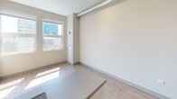 Located at 2112 S Michigan Ave in Chicago's dynamic South Loop neighborhood, this single-floor unit offers a clean, modern aesthetic throughout. The open living area features light wood-tone flooring, neutral warm-beige walls, and an exposed industrial-style ductwork detail running along the ceiling, adding a subtle urban character to the space. Natural light filters in through a window offering city views, brightening the interior with a welcoming glow.

The kitchen is thoughtfully designed with white cabinetry extending to the ceiling for generous storage, stainless steel appliances including a full-size refrigerator and dishwasher, a built-in cooktop, and a countertop island that provides additional prep space and opens naturally into the living area — ideal for both everyday functionality and entertaining.

The bathroom is outfitted with a full walk-in shower featuring built-in shelving, a curved chrome shower rod, chrome grab bars, and a clean white surround, complemented by a sleek vanity. The sliding glass door adds a contemporary touch while maximizing the use of space.

Throughout the unit, the consistent use of light flooring, neutral tones, and modern fixtures creates a cohesive and polished living environment well-suited to urban Chicago living.