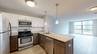 Located in Chicago's vibrant West Loop neighborhood, this well-appointed residence at 180 N Jefferson St offers a thoughtfully designed single-floor layout with modern finishes throughout. The open-concept kitchen serves as the centerpiece of the living space, featuring granite countertops, a peninsula with a built-in sink, and a full suite of stainless steel appliances including a gas range, microwave, and dishwasher. White upper cabinetry paired with dark wood lower cabinets creates a striking two-tone contrast, complemented by a classic subway tile backsplash and pendant lighting above the peninsula. Light wood-style flooring runs seamlessly throughout the space, adding warmth and continuity. The living area is generously proportioned and bathed in natural light through expansive floor-to-ceiling windows that frame city views. A dedicated in-unit laundry area provides added convenience. The bathroom is finished with a dark granite vanity top, a wood-tone cabinet base, a framed mirror, and a tiled tub-shower combination, all accented by brushed nickel fixtures. Neutral wall tones and clean lines throughout contribute to a calm, contemporary ambiance well-suited for urban living.