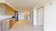 Located at 3180 NW 79th St in Miami, FL, this one-bedroom, one-bathroom unit offers a well-designed, efficient layout spread across a single floor. The open-concept living and kitchen area is finished with large-format light tile flooring throughout, creating a clean and cohesive aesthetic. The kitchen is a standout feature, equipped with warm wood-tone cabinetry extending to the ceiling, granite countertops, and a full suite of stainless steel appliances including a refrigerator, electric range, built-in microwave, and dishwasher. Track lighting overhead ensures the space is well-lit and functional. A hallway leads to multiple closets — four in total — providing generous storage options rarely found in comparably sized units. The bedroom is a bright, tranquil retreat featuring a large floor-to-ceiling window that frames expansive views of the Miami skyline and surrounding greenery, flooding the room with natural light. The open living area similarly benefits from oversized windows and a ceiling fan, enhancing comfort and airflow. The unit's clean white walls, modern finishes, and abundant storage make it a practical and stylish residence in the heart of Miami.