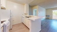 Located on Atlantic Avenue in Long Beach, California, this one-bedroom, one-bathroom unit offers a practical and comfortable layout across a single floor. The open-concept living and kitchen area forms the heart of the space, featuring smooth hardwood-style flooring that extends throughout the main living areas. The kitchen is defined by a peninsula counter with tile detailing, white cabinetry, a stainless steel sink, and a dishwasher, making it both functional and easy to navigate. The living area is bright and airy, benefiting from natural light that pours in through a large sliding glass door fitted with vertical blinds. The slider opens to a private balcony, offering views of surrounding greenery. A wall-mounted air conditioning unit provides climate control in the main living space. The bedroom is a well-proportioned retreat featuring plush carpeting, a ceiling fan with integrated lighting, built-in closet storage, and a window that brings in additional natural light. The bathroom is generously appointed with an extended tile countertop vanity, ample under-counter cabinetry, a large wall mirror, and a tiled shower enclosure. Textured ceilings are present throughout, adding a classic residential character to the space.