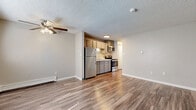 Located at 12641 W Mississippi Ave in Lakewood, Colorado, this one-bedroom, two-bathroom unit offers a well-organized single-floor layout designed for comfortable everyday living. Wood-look plank flooring runs throughout the main living areas, complementing the neutral beige tones on the walls and crisp white baseboards that give the space a clean, cohesive feel. Textured ceilings are present throughout.

The open living area is bright and functional, featuring a ceiling fan with light fixture, a wall-mounted A/C unit, and a baseboard heater, providing year-round climate control. A window with blinds allows natural light to fill the room. The kitchen opens directly to the living space and is equipped with stainless steel appliances — including a refrigerator, electric range, and microwave — alongside gray cabinetry and a single-basin sink.

The bedroom offers plush carpeting, a ceiling fan, a window with blinds, and a baseboard heater. A mirrored sliding-door closet provides convenient storage, and additional closets are found throughout the unit, totaling three. The two bathrooms include a full tub-shower combination with white tile surround and a window for ventilation. A hallway connects the various rooms, contributing to the unit's efficient and practical flow.