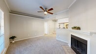 Located at 315 Valleywood Dr in Spring, TX, this 2-bedroom, 3-bathroom single-story home offers a well-designed layout with a warm, neutral aesthetic throughout. The living room is a welcoming centerpiece, featuring plush carpeting, crown molding, a ceiling fan with light fixture, and a classic wood-burning fireplace with a tiled hearth. A half-wall passthrough connects the living area to the galley-style kitchen, which is outfitted with white shaker cabinetry, granite-look countertops, light hardwood flooring, and stainless steel appliances. Both bedrooms are carpeted and bright, benefiting from large windows that invite natural light, along with ceiling fans for added comfort. The spacious primary bedroom includes direct access to an en-suite bathroom featuring a single vanity with granite countertops, white cabinetry, and wood-look flooring. The bathrooms are clean and functional, with one featuring a full tub-shower combo with white subway tile surround. Closets are equipped with wire shelving systems for practical storage. The overall ambiance is light, neutral, and move-in ready, with consistent finishes that create a cohesive feel across the entire home.