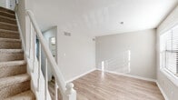 Located at 2002 Cedar Fork Dr in Greensboro, NC, this two-story, 2-bedroom, 2-bathroom home offers a well-organized layout across two floors. The main level features a bright living room with light-toned luxury vinyl plank flooring, neutral warm-gray walls, and a white staircase railing leading to the upper level. Natural light streams in through window treatments, lending a clean, airy feel throughout. The combined dining room and kitchen is a functional highlight, featuring crisp white shaker-style cabinetry, white countertops, a stainless steel dishwasher, range, and refrigerator — all complemented by wood-look flooring and a window for added brightness. Upstairs, both bedrooms are carpeted for comfort and include ceiling fans and ample closet space. The primary bedroom offers a generous footprint with dedicated closet storage, while the secondary bedroom features louvered bifold closet doors. The two bathrooms include wood-look flooring; one features a tub/shower combination with tiled surround and louvered storage closet. With seven closets total, a dedicated laundry area, and two staircases providing convenient access, this home prioritizes practical storage and efficient use of space. Textured ceilings are present throughout.