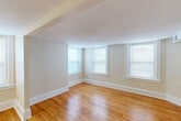 Located at 32 Church St in Norwich, Connecticut, this single-floor unit offers a practical and well-organized layout across a modest footprint. Warm hardwood flooring flows throughout much of the space, creating a cohesive and inviting atmosphere. An entry hallway with an intercom panel welcomes you in, leading to the main living areas.

The combined dining and living room is a highlight of the unit, featuring multiple windows that allow generous natural light to fill the room. A textured ceiling and clean white trim complement the warm wood floors, giving the space a bright, open feel. An adjacent room, visible through a wide open archway, extends the living area further and offers additional flexibility.

The kitchen provides functional space for meal preparation, while a dedicated utility room adds practical storage and service capabilities. Two closets offer convenient storage throughout the unit.

The bathroom is well-appointed with a full tub and shower combination, a vanity with under-cabinet storage, a lighted mirror, and hardwood flooring, maintaining a clean and bright aesthetic. Additional rooms feature large windows with blinds, textured ceilings, and durable laminate or hardwood flooring in neutral tones, making them versatile for various uses. Overall, the unit presents a clean, move-in ready space in a convenient Norwich location.