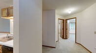 Located at 802 W Main St in Waunakee, Wisconsin, this two-bedroom, one-bathroom single-floor unit offers a straightforward and functional layout designed for comfortable everyday living. The open living area is finished with neutral-toned carpet and cream-colored walls, creating a clean and understated atmosphere. A ceiling fan with a light fixture provides both ventilation and ambient lighting, while a sliding door with vertical blinds connects the living space to the outdoors and allows natural light to filter in. The adjacent kitchen features warm wood-toned cabinetry and includes standard appliances, keeping the cooking area practical and accessible.

The primary bedroom is generously sized and features a ceiling fan, carpeted floors, and a window with vertical blinds that brings in natural light. The second bedroom is more compact, offering a built-in closet with wood-panel bifold doors, neutral carpet, and ample wall outlets. A connecting hallway links the bedrooms to the full bathroom, which is equipped with a tub-shower combination, a single vanity with sink, a toilet, and stone-look tile flooring. Grab bars in the shower area add an accessibility-conscious touch. Throughout the unit, warm wood-toned trim and doors provide consistent design continuity.