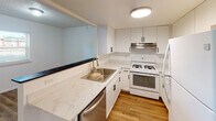 Located at 4100 W 19th Ave in Stillwater, Oklahoma, this two-floor home offers a practical and updated living environment with a clean, neutral aesthetic throughout. The kitchen is a standout feature, equipped with white cabinetry accented by black hardware, marble-look quartz countertops, a stainless steel sink, a gas range, dishwasher, and refrigerator — all complemented by warm hardwood-style flooring and a pass-through window that connects to the adjacent living area. The living space showcases the same hardwood-style flooring and is highlighted by a distinctive exposed brick column, adding a touch of architectural character to the otherwise modern interior. Bedrooms are finished with plush carpeting and ceiling fans, providing comfort and climate control. Windows with blinds allow for natural light while maintaining privacy. The bathroom features a tub-shower combination with tile surround, a toilet, wood-look flooring, and a vanity with a quartz-style countertop, white cabinetry, and a round mirror with modern wall-mounted lighting. Textured ceilings are consistent throughout the home, contributing to its classic residential character. The two-floor layout offers practical separation of living and private spaces.
