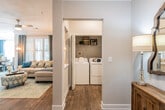 This single-story residence offers a thoughtfully designed layout with a warm, cohesive aesthetic highlighted by wood-look flooring, crown molding, and neutral wall tones throughout the main living areas. The galley-style kitchen is well-equipped, featuring white cabinetry, granite countertops, stainless steel appliances including a gas range and dishwasher, and a stainless sink — all complemented by a decorative vertical planter wall accent. Adjacent to the kitchen, the dining area is bathed in natural light from multiple windows dressed with teal plaid curtains and wood blinds, creating an inviting atmosphere. The living room continues the bright, airy feel with additional windows. A dedicated in-unit laundry room provides added convenience with side-by-side washer and dryer. The bedrooms offer comfort and character — one features a bold teal accent wall, while another includes a ceiling fan, private door access, and generous natural light. The full bathroom includes a dual-sink vanity with granite countertops, wood-look flooring, and a tub-shower combination. A welcoming hallway with crown molding and warm wood cabinetry connects the rooms seamlessly throughout.