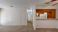 Located at 4501 Summerhill Rd in Texarkana, TX, this single-floor residence offers a functional and comfortable layout across two bedrooms and two bathrooms. The combined living and dining area is carpeted throughout, with a ceiling fan overhead and a glass patio door that invites natural light and outdoor access. The kitchen is positioned adjacent to the living area behind a half-wall pass-through counter, featuring warm wood cabinetry, a light-toned countertop, and white appliances including a refrigerator, stove, and microwave. A hallway connects the living spaces to the private quarters, maintaining a clear and efficient flow throughout. The primary bedroom is a well-proportioned retreat with a ceiling fan, a wide bay-style window for natural light, and access to a walk-in closet equipped with built-in shelving and a hanging rod. The second bedroom also features a ceiling fan and a window, offering a comfortable and functional space. Both bathrooms are well-appointed, with one featuring a wood-toned vanity, granite-style countertop, and a tiled tub-shower combination. Textured ceilings are consistent throughout the home, contributing to the overall character of the space.